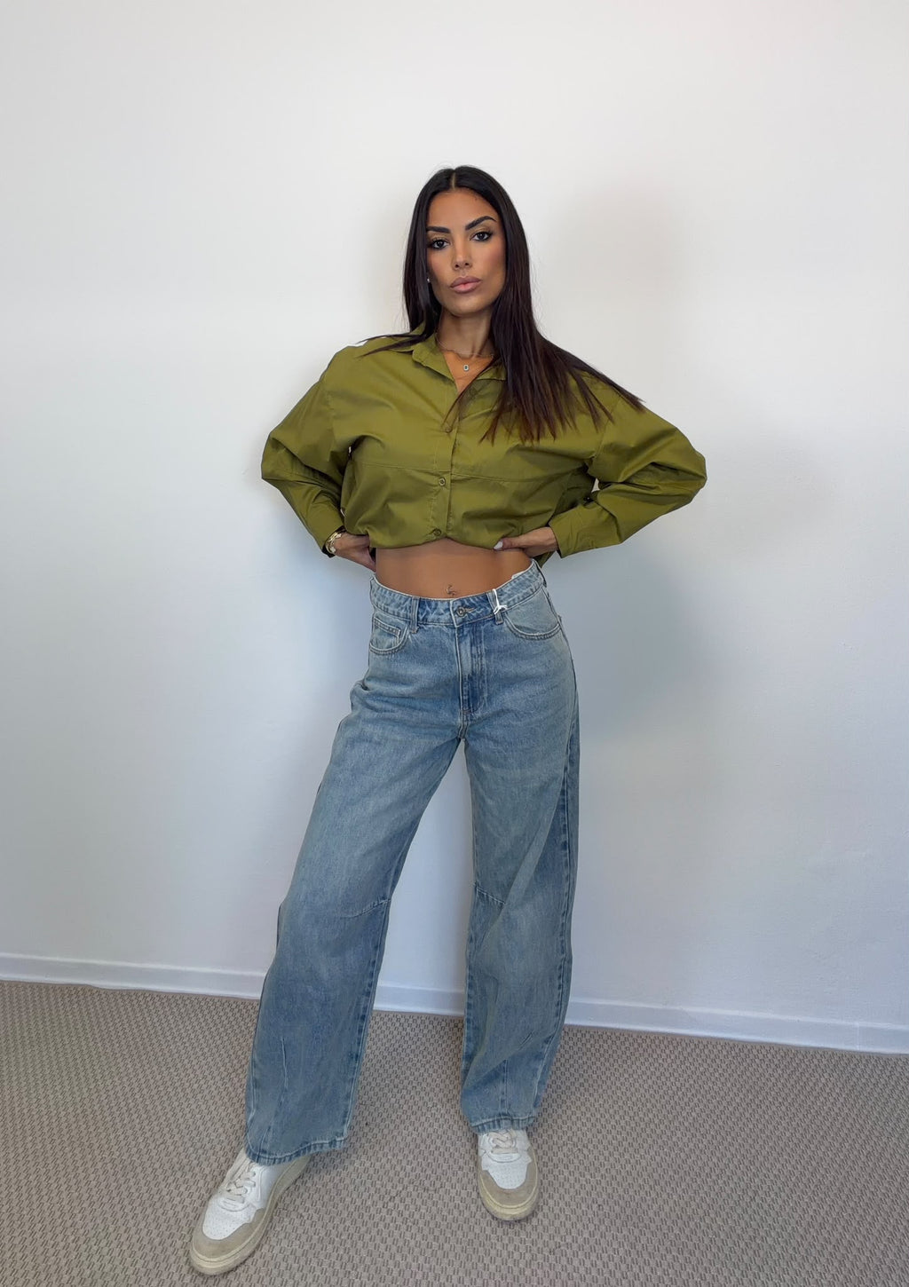 Camicia crop verde e jeans barrel in lavaggio chiaro indossati insieme, figura intera.