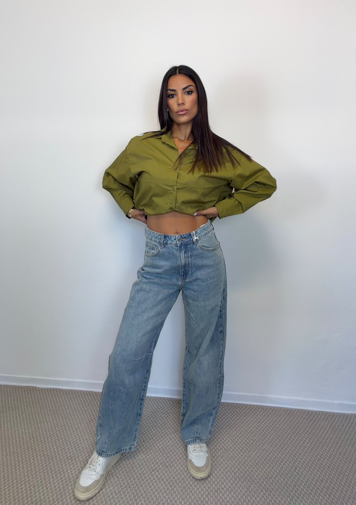 Camicia crop verde e jeans barrel in lavaggio chiaro indossati insieme, figura intera.