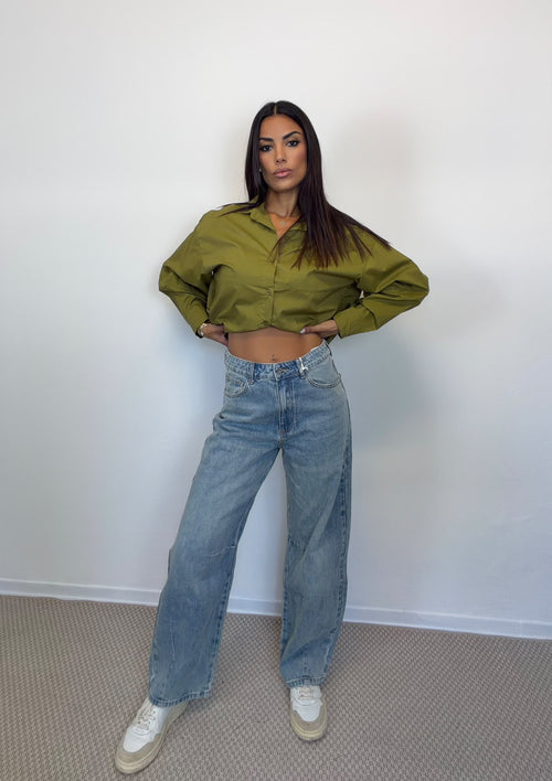 Camicia crop verde e jeans barrel in lavaggio chiaro indossati insieme, figura intera.