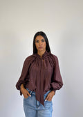 Camicia elegante bordeaux con fiocco al collo e maniche ampie, indossata.