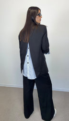 Giacca Lumina nera con inserto bianco sul retro e pantaloni neri, vista posteriore.