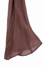 Dettaglio del fondo manica ampio della camicia marrone con pizzo.
