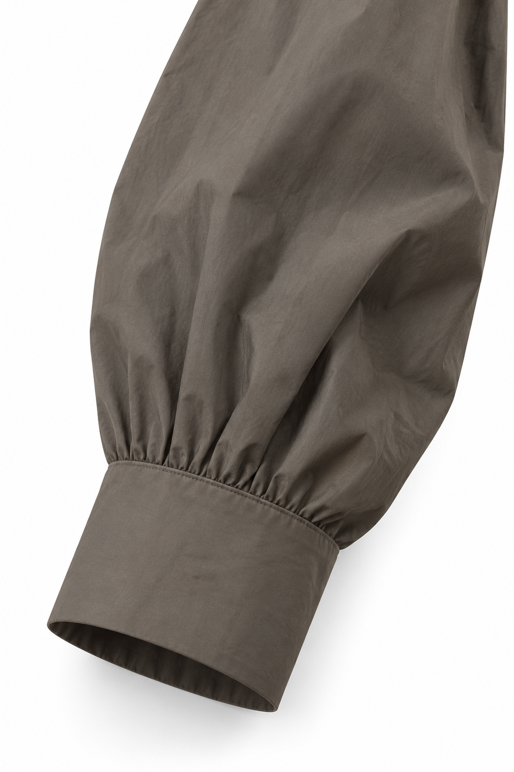 Dettaglio del polsino e della manica della camicia in popeline, su fondo bianco.