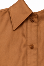 Dettaglio del colletto e dei bottoni della camicia color cammello.