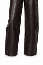 Dettaglio del fondo gamba dei pantaloni marrone scuro del coordinato Riviera, su fondo bianco.