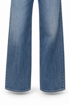 Dettaglio delle gambe ampie e degli orli dei jeans con tasche in ecopelle, su fondo bianco.