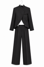 Tailleur coreano nero non indossato, giacca con apertura curva e pantaloni ampi, vista frontale su fondo bianco.
