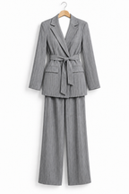 Tailleur gessato grigio su gruccia, vista frontale della giacca con cintura e pantaloni.