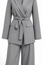 Tailleur gessato grigio non indossato, dettaglio della cintura annodata e delle righe.
